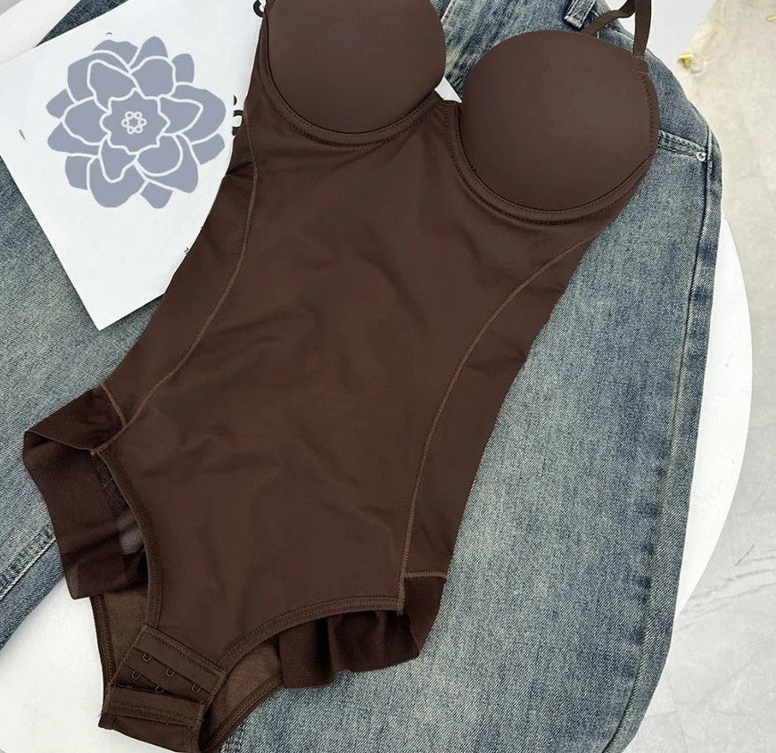 Brown thong bodysuit with molded cups and thin straps, laid flat on denim