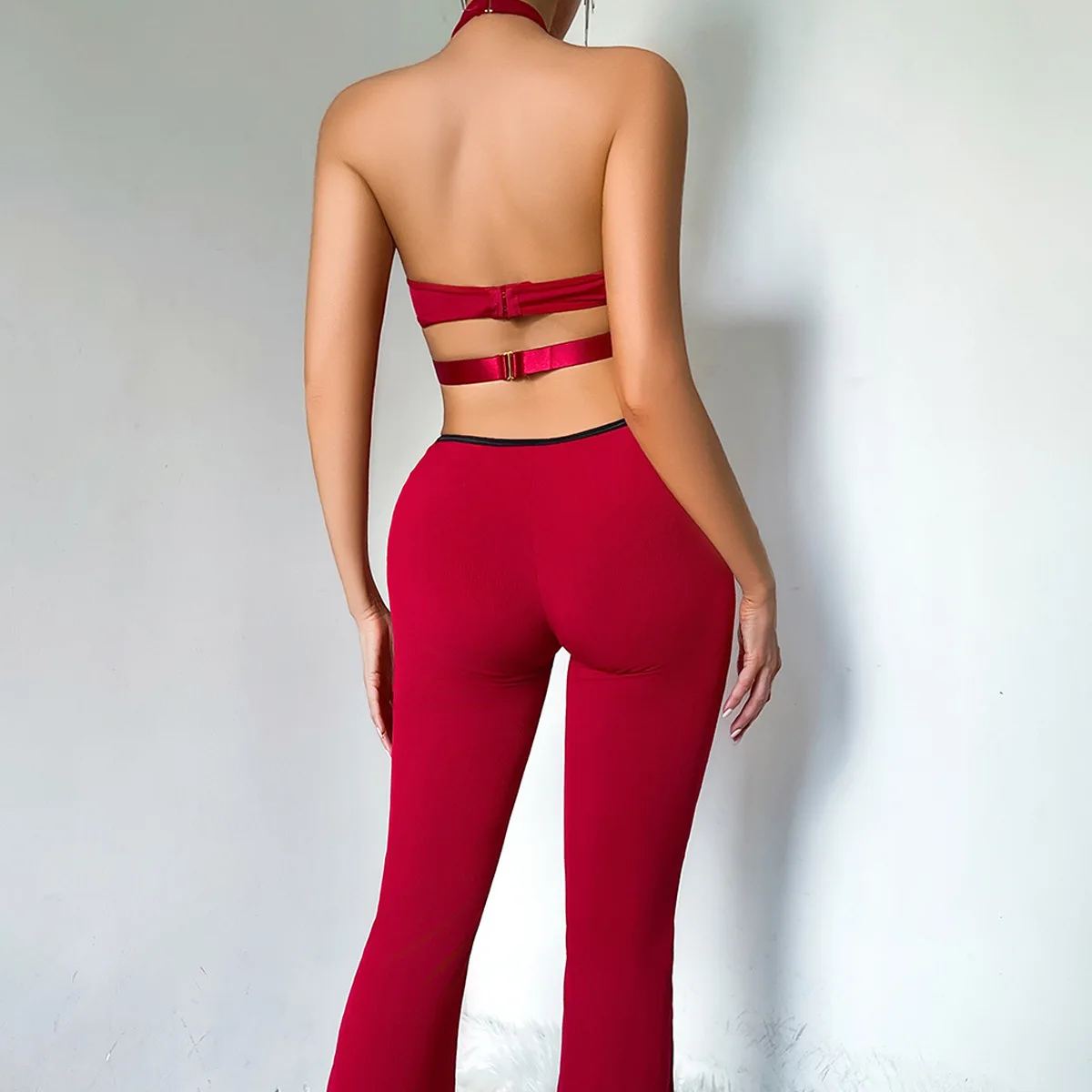The burgundy catsuit from the back: bare back, one clasp strap, flared legs