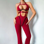 Burgundy halter catsuit worn with hands on hips, open at both sides of the waist